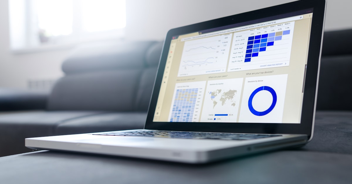 A laptop displaying a clean analytics dashboard with bar charts and a world map, on a calm table — the data behind how your business actually shows up in search.