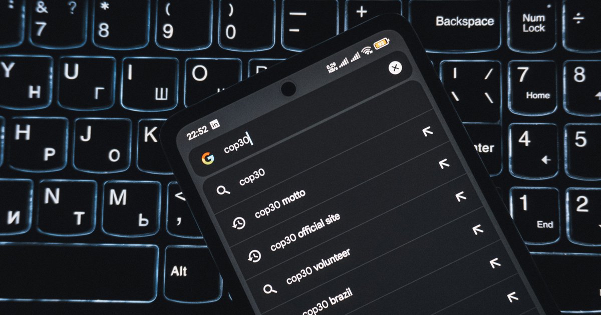 A smartphone resting on a backlit keyboard, displaying a Google search where an AI Overview recommends a local business